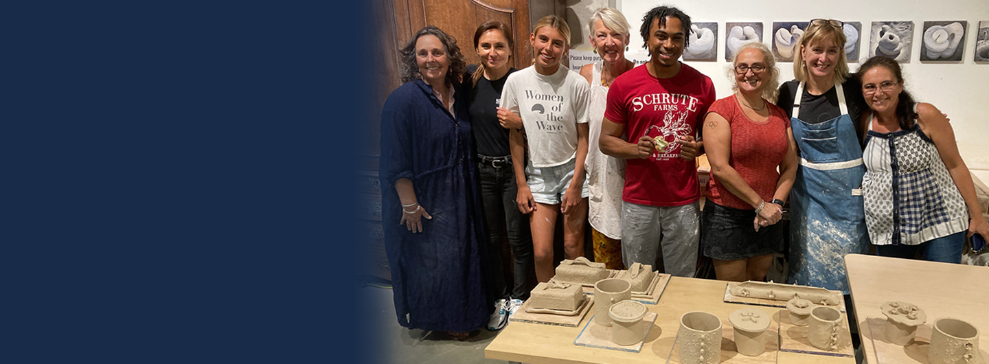 Students and instructors standing behind ceramics projects