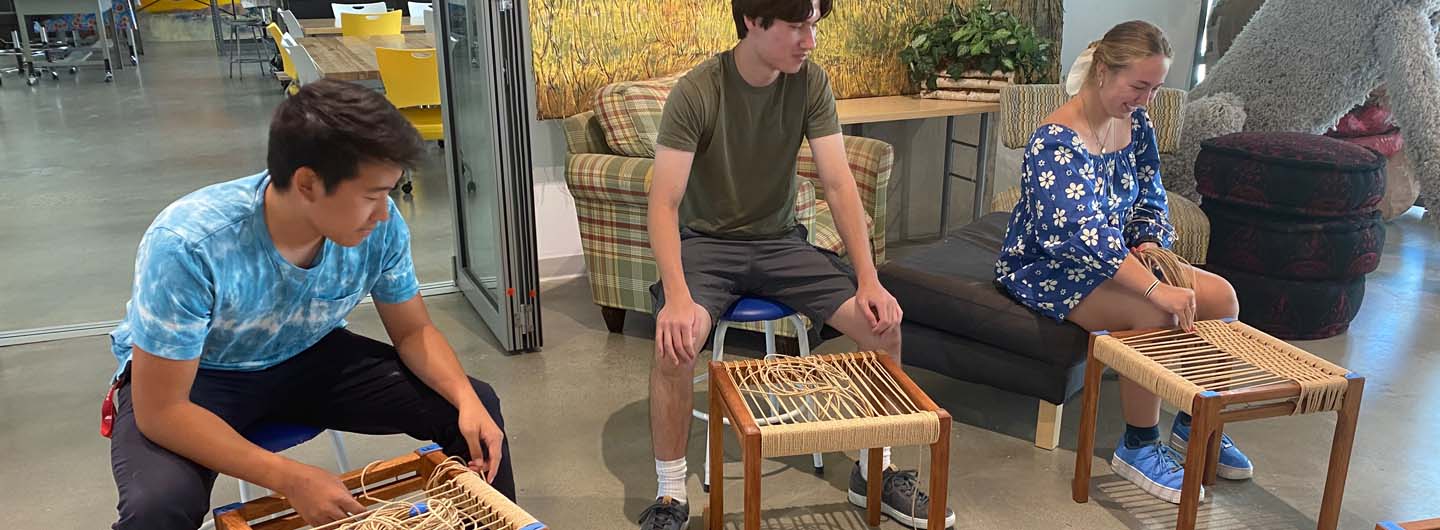 Students weaving chairs at Craft Center